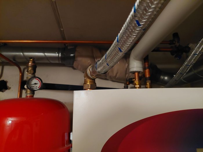 Värmesystem med röda och kopparledningar, expansionskärl och tryckmätare.