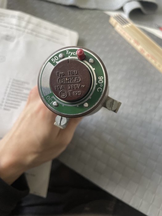 Hand håller en Tryck- och temperaturvakt av märket BIRKA, typ TB, med teknisk specifikation.