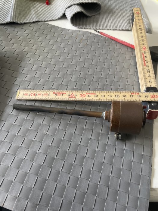 Tumstock och kakelskärare på ett grått kakelgolv under installation.