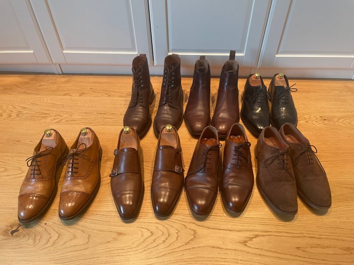 Samling herrskor på trägolv med Yanko kängor till vänster, Meermin oxfords och Herrings semi-brogues framtill, Loake brogues till höger.