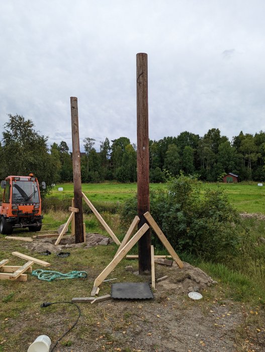 Två handgrävda stolpar restes vertikalt med förstärkningar av trä för en framtida gungställning.