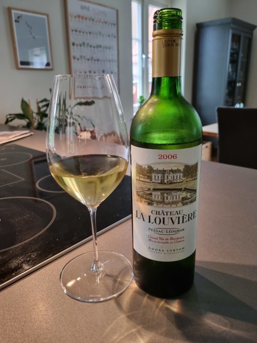 Vinflaska av Château La Louvière Vit Bordeaux årgång 2006 och glas med vin.