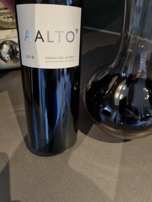 Flaska rödvin AALTO 2018 från Ribera del Duero intill en dekanteringskanna.