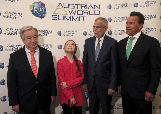 Unge person står bredvid tre äldre herrar vid Austrian World Summit.