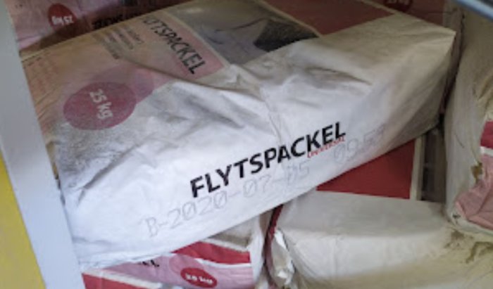 Trasiga säckar med flytspackel märkta "B-20200725" staplade på pall i butik.