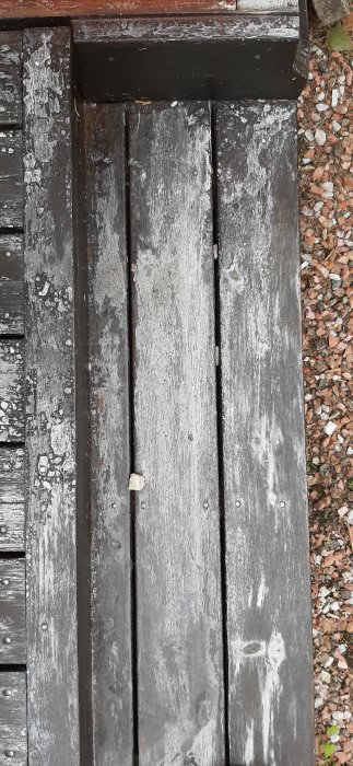 Trätrall i behov av underhåll med flagnande grå färg och rostiga spikar.