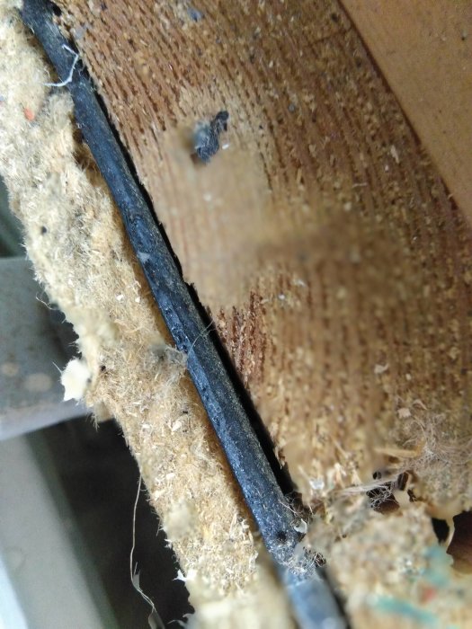 Närbild på isolering och elkabel i en vägg under en renovering.