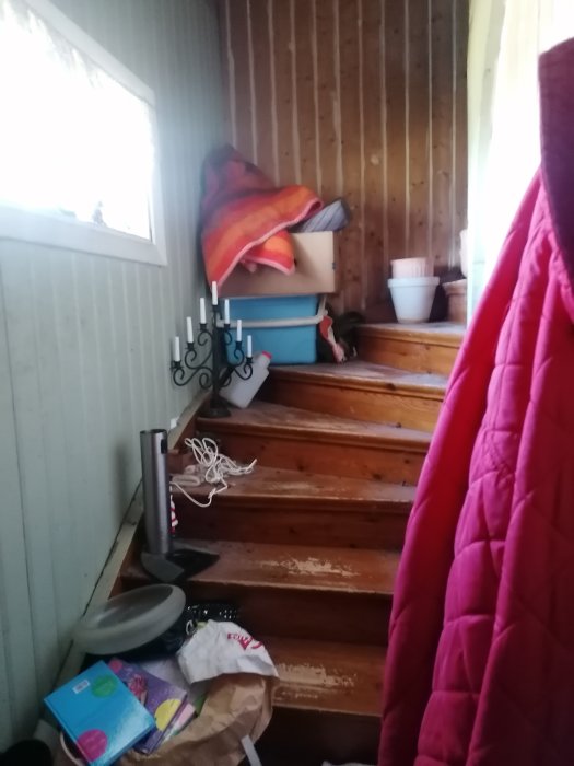 Trappa med oordning – lådor, filtar och diverse föremål utspridda på stegen.