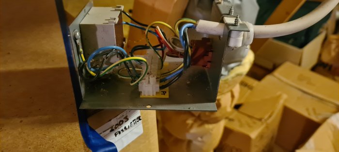Öppen elanslutningslåda med sladdar och kopplingar framför kartonger.