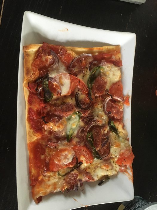 Hemgjord pizza med tomatsås, saltrulle, rödlök, tomat, ost, mozzarella, padrones och salami.