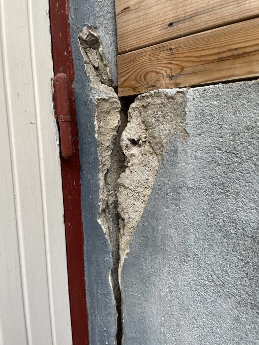 Sprucken puts vid en dörrkarm med synlig underliggande trästruktur.