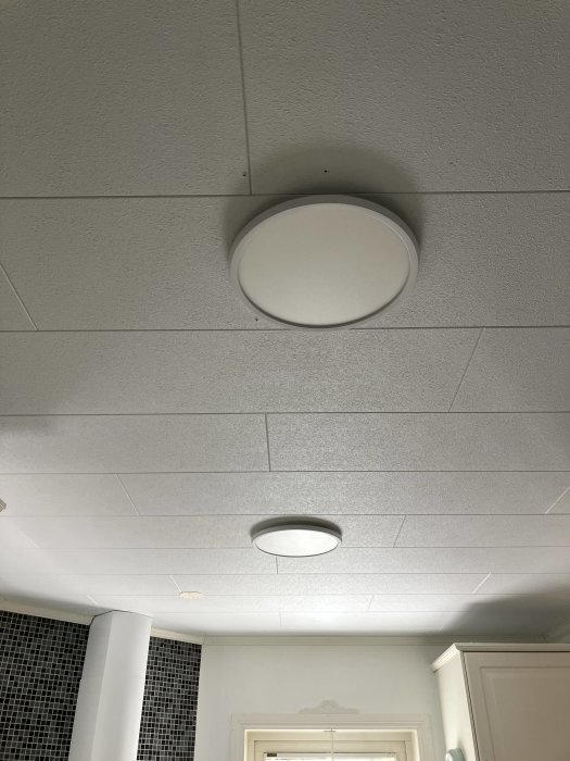 Tak med två inbyggda LED-lampor och akustikplattor i ett kök.