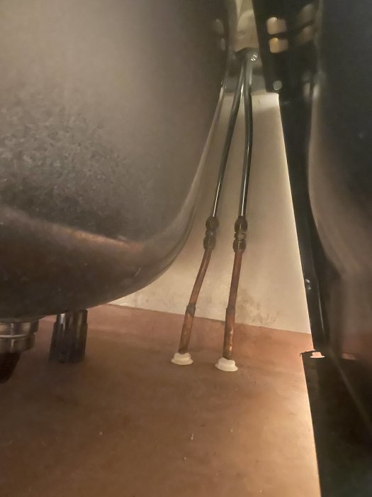 Korroderade kopparrör under en badkarssida på ett badrumsrenoveringsprojekt