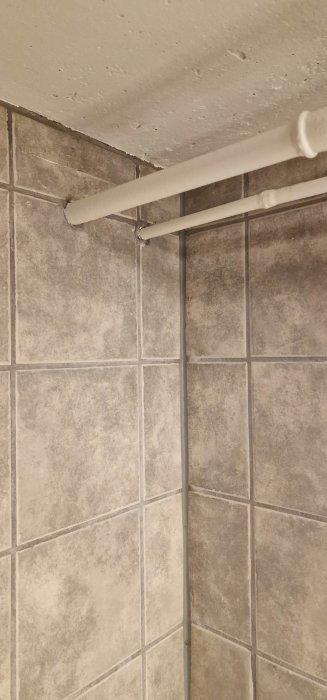 Vattenrör framför kaklade väggar och under en ruff takyta.