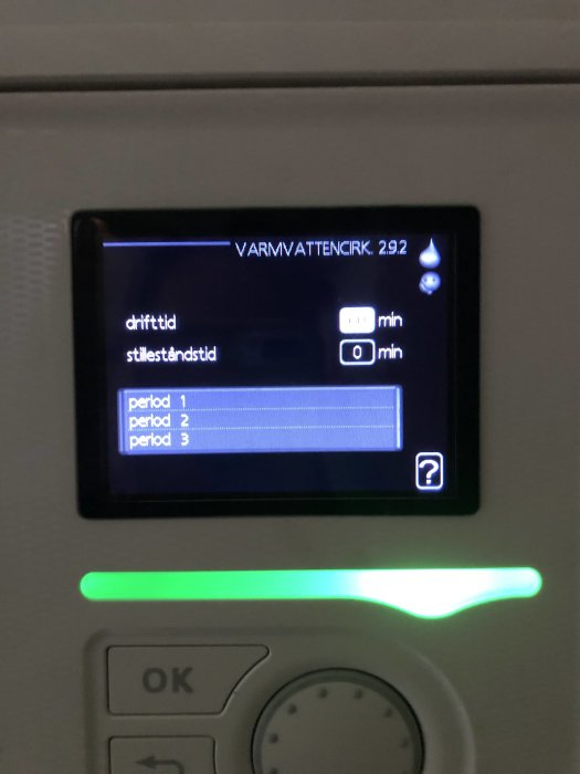 Digital display av varmvattencirkulationsenhet med inställningsmeny och grönt statusljus.