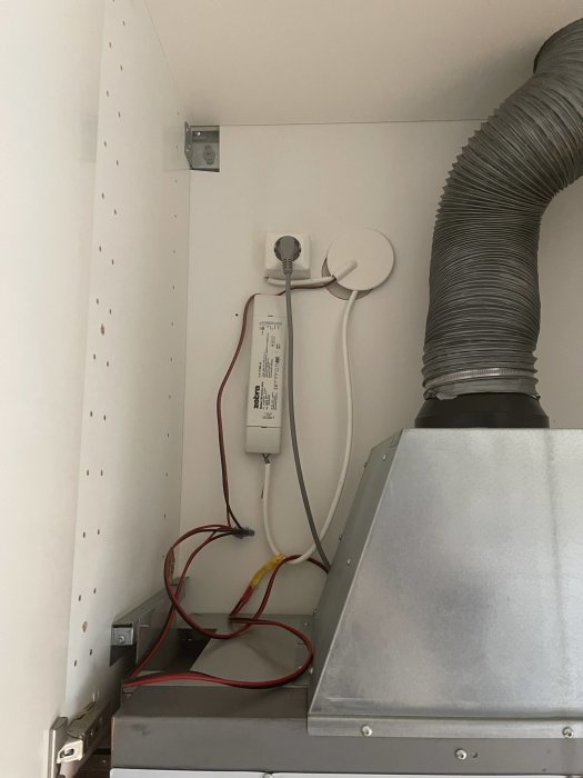 Installation av köksfläkt och elektronik med synliga ledningar och ventilationsrör.