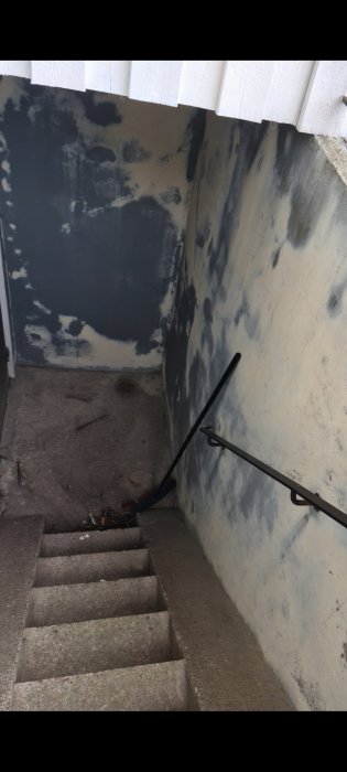 Trappa med slitna betongsteg och mögliga väggar som behöver renovering.