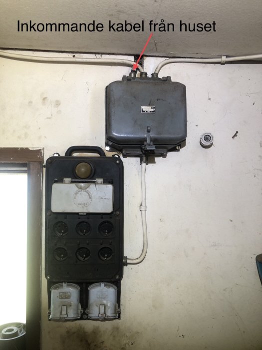 Äldre elcentral med säkringsskåp och ett antal uttag, märkt där inkommande kabel från huset är ansluten.