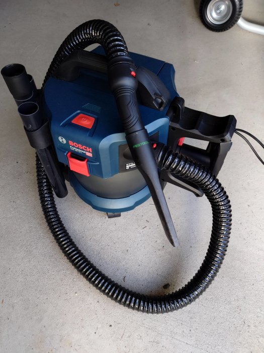 Bosch dammsugare med Festool fogmunstycke anslutet, på ett garagegolv.