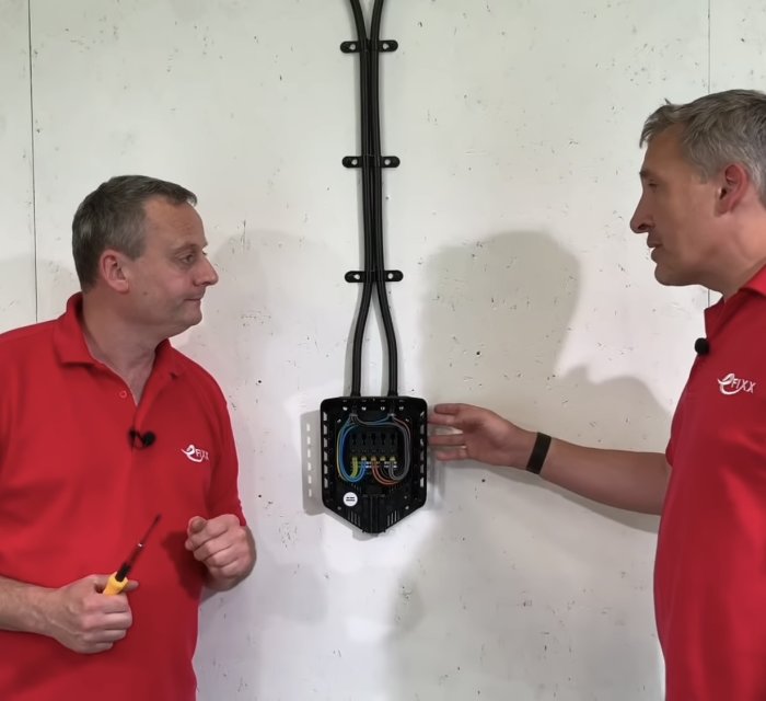 Två elektriker diskuterar installation av en Easee-laddbox med synlig kabeldragning.