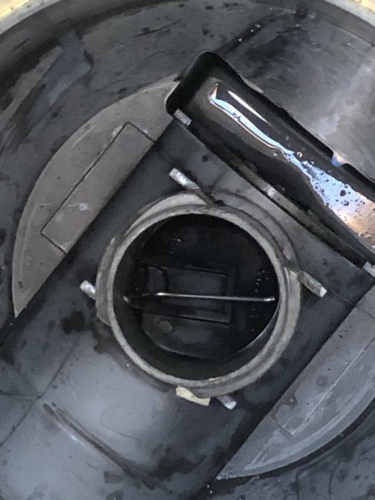 Närbild av en tvättmaskins felplacerade del invändigt, synlig genom en öppning.