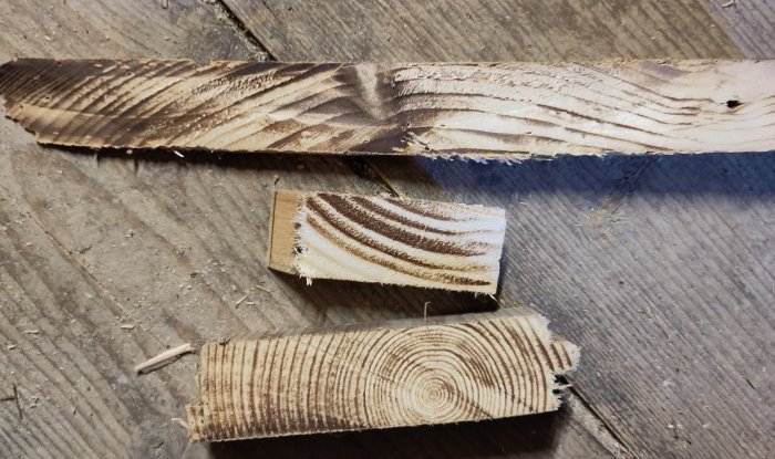 Träbitar med sågade mönster på ett smutsigt trägolv.