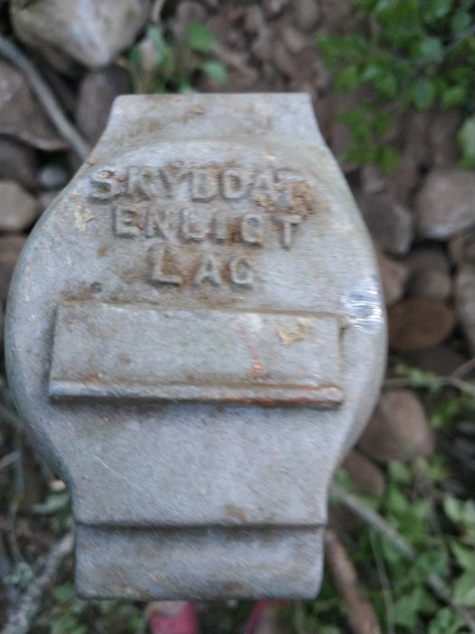 Suddig bild av en gammal stenplatta med texten "SKYDDAT ENLIGT LAG".