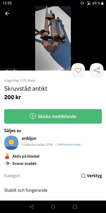 Antikt skruvstäd av metall på en vit bakgrund till salu.