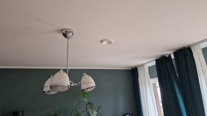 Tak med ventilation och lampa, gröna gardiner och fönster, renovering pågår.