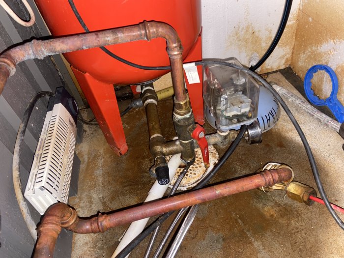 Installation av hydropress och tryckströmbrytare med synliga kopplingar och tillfällig slang.