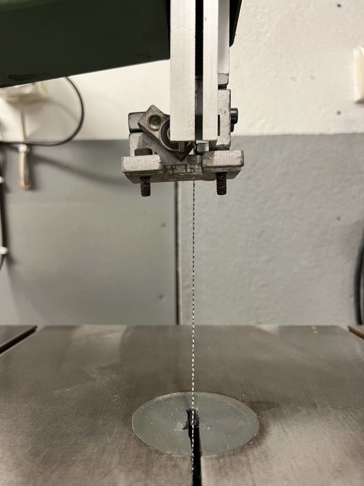 Bandklinga av en bandsåg sedd framifrån där klingan går genom arbetsbordets skåra.