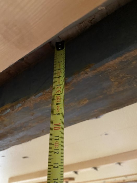 Mätverktyg visar avståndet mellan två träytor i en byggkonstruktion.