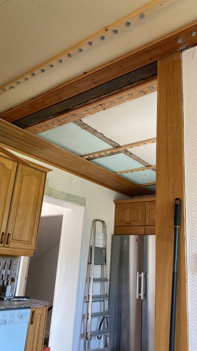 Renoveringsprojekt i kök med exponerade takbjälkar, trappstege och skåp.