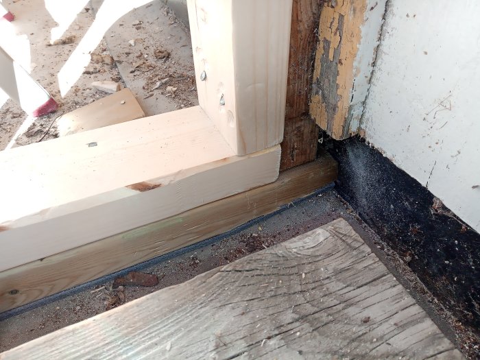 Detaljbild av ett hörn vid altandörr med tecken på rötskador och fuktinträngning.