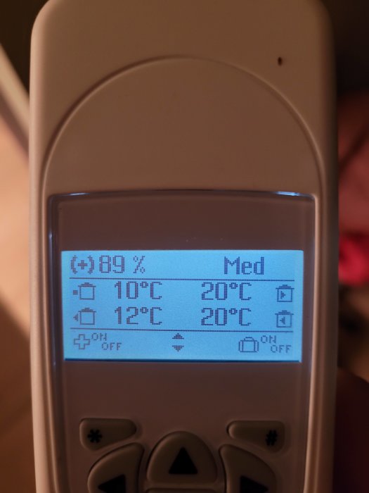 Digital termostat visar temperaturinställningar och luftfuktighet på en bakgrundsbelyst LCD-skärm.