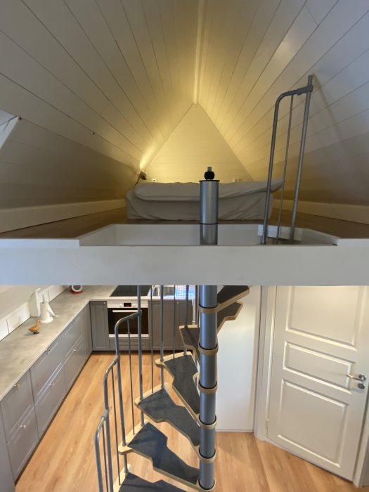 Renoverad lägenhet med sovloft och spiraltrappa som leder ner till ett modernt kök.