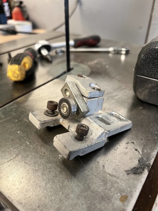 Sprucket hjulhus med hjul på arbetsbänk, verktyg i bakgrunden, planer på 3D-utskrivet ersättningshus.