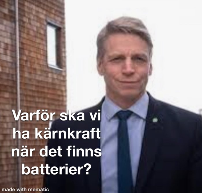 Man i kostym framför tegelbyggnad med text “Varför ska vi ha kärnkraft när det finns batterier?”