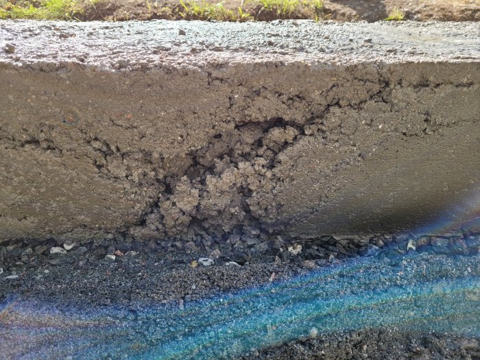 Närbild på en grundplatta med en synlig spricka och ojämn konsistens i betongen.