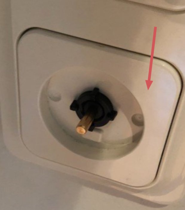 Närbild på en väggmonterad dimmerknapp med borttagen mutter, inre ram synlig.