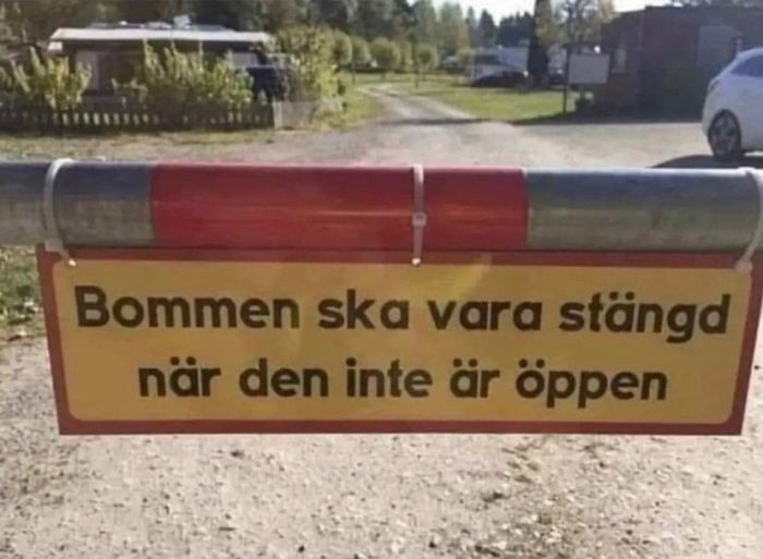 Skylt som säger "Bommen ska vara stängd när den inte är öppen" med en bom i bakgrunden.