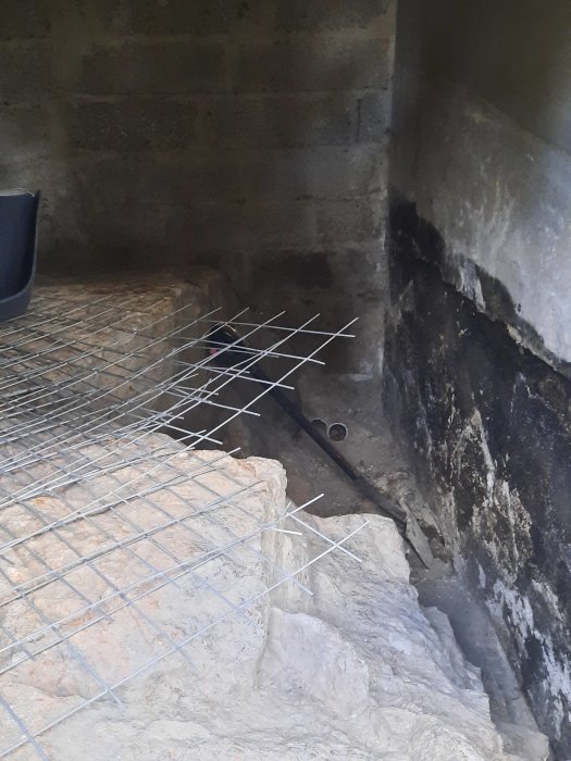 Bild på en krypgrund med osammanhängande isolering och nätkonstruktion vid en betongvägg som visar möjliga fuktproblem.