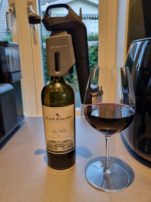 Flaska av Black Stallion Cabernet Sauvignon med Coravin-system och ett glas rödvin.