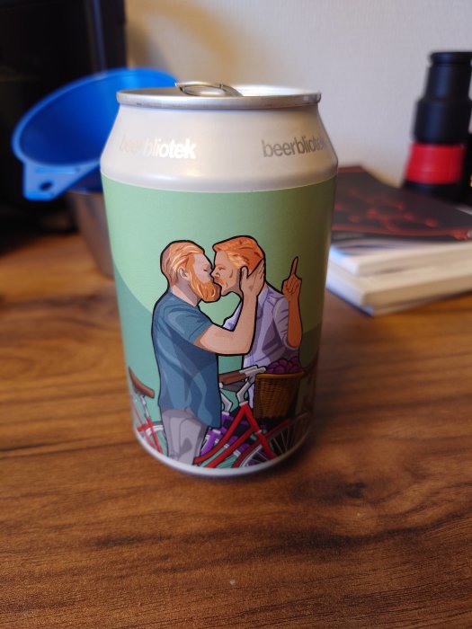 Ölburk från Beerbliotek med illustration av två personer som kysser varandra, står på ett träbord.