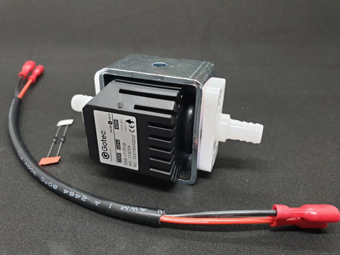 Svart elektrisk pump med elkabel och kopplingsdelar mot en mörk bakgrund.