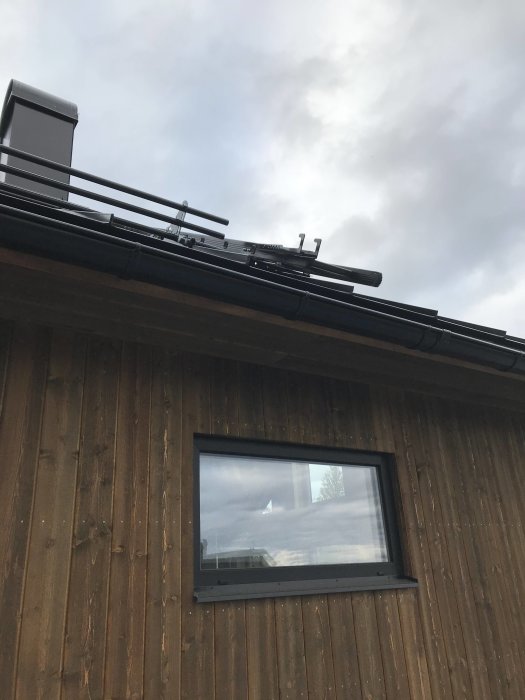 Nyinstallerad skorsten på hus med träpanel och fönster utan foder, samt glidskydd på steg.