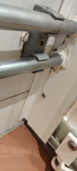 Skadat dörrlås och trasigt karmområde på en vit innerdörr, behov av reparation.