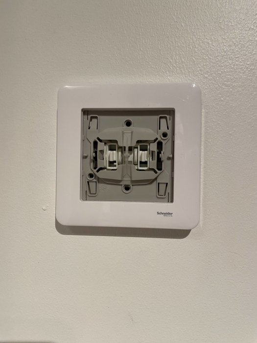 Öppen eluttagsinstallation på vägg från Schneider Electric.