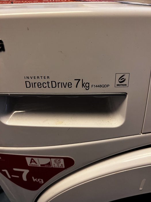 Närbild av en vit tvättmaskin, DirectDrive 7 kg, med modellnummer och energimärkning synliga.