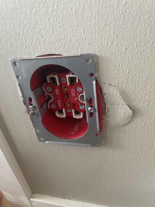 En öppen eldosa i vägg med synliga ledningar och kontakter, ej färdigställd installation.